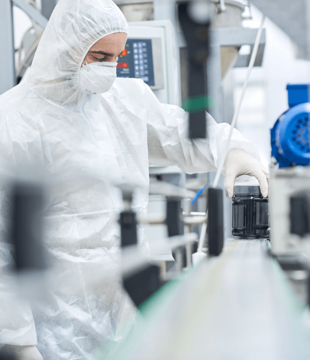 scientist in full safety gear including hood, mask and gloves working at machine