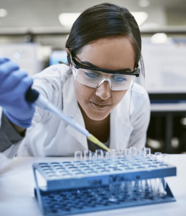 scientist wearing blue gloves and safety goggles working with test tubes