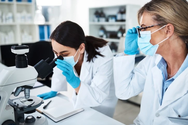 2 women scientists wearing gloves and masks