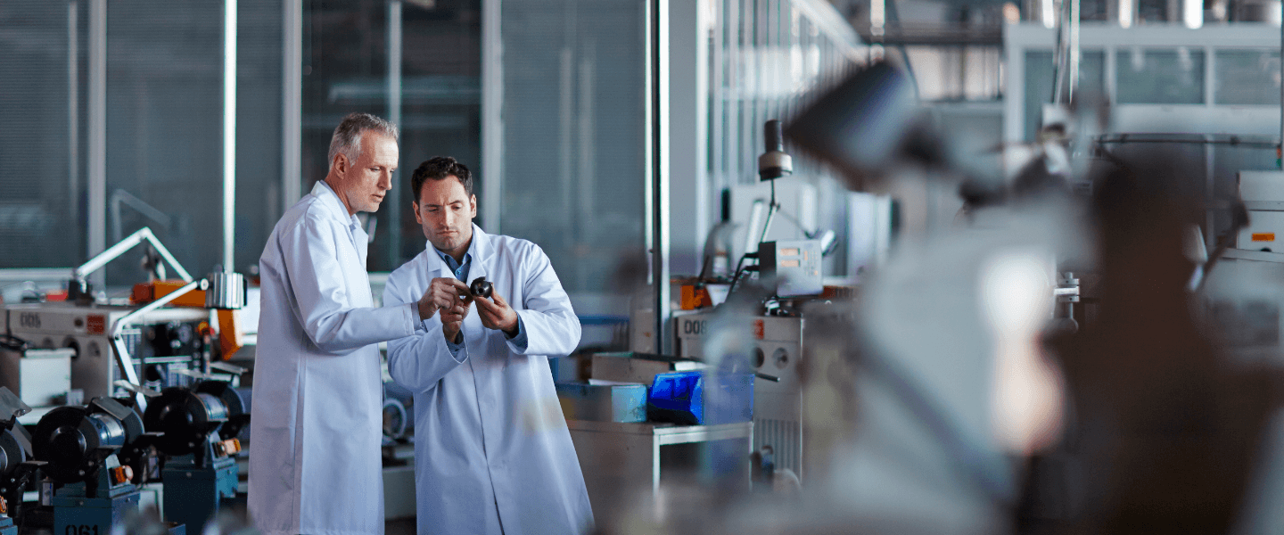 two scientists standing in a lab discussing product one of them is holding