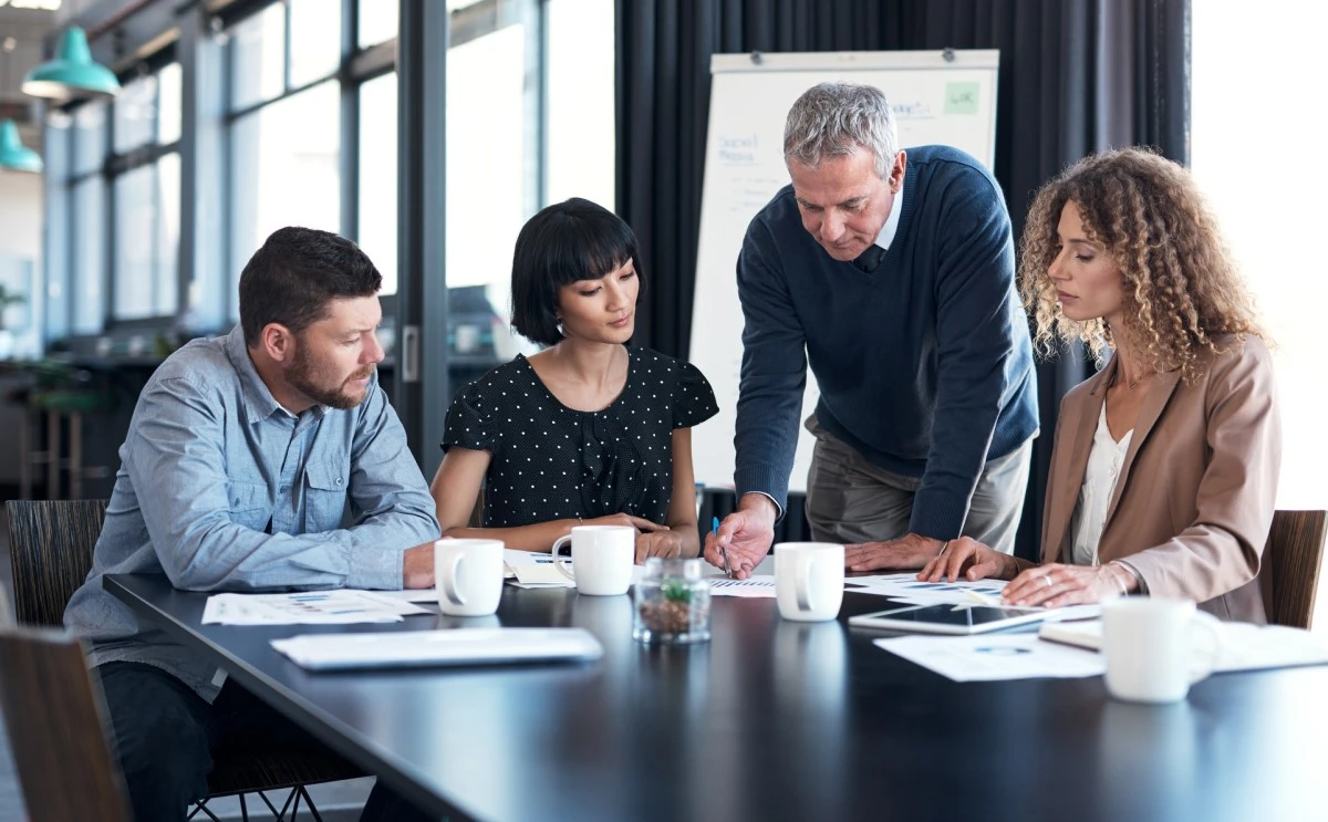 team of four working together at a table with documents on