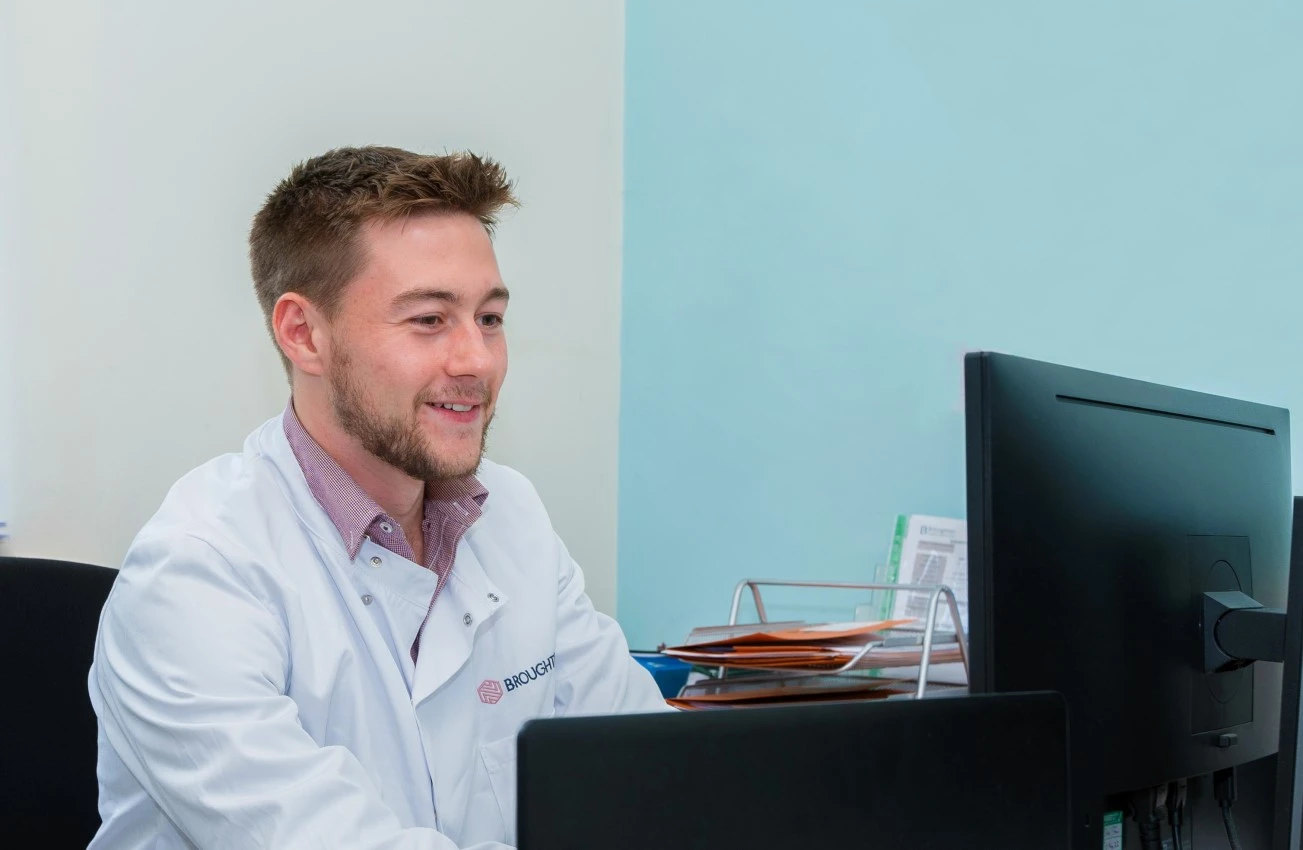 Broughton scientist wearing lab coat working at a computer