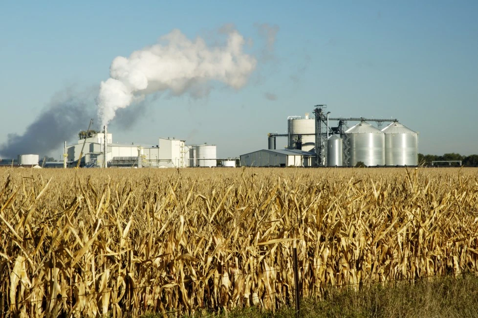 U.S. farm field with factory in the background