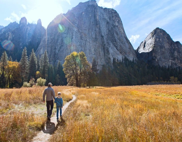 father and son walking outdoors in nature with mountains in the background