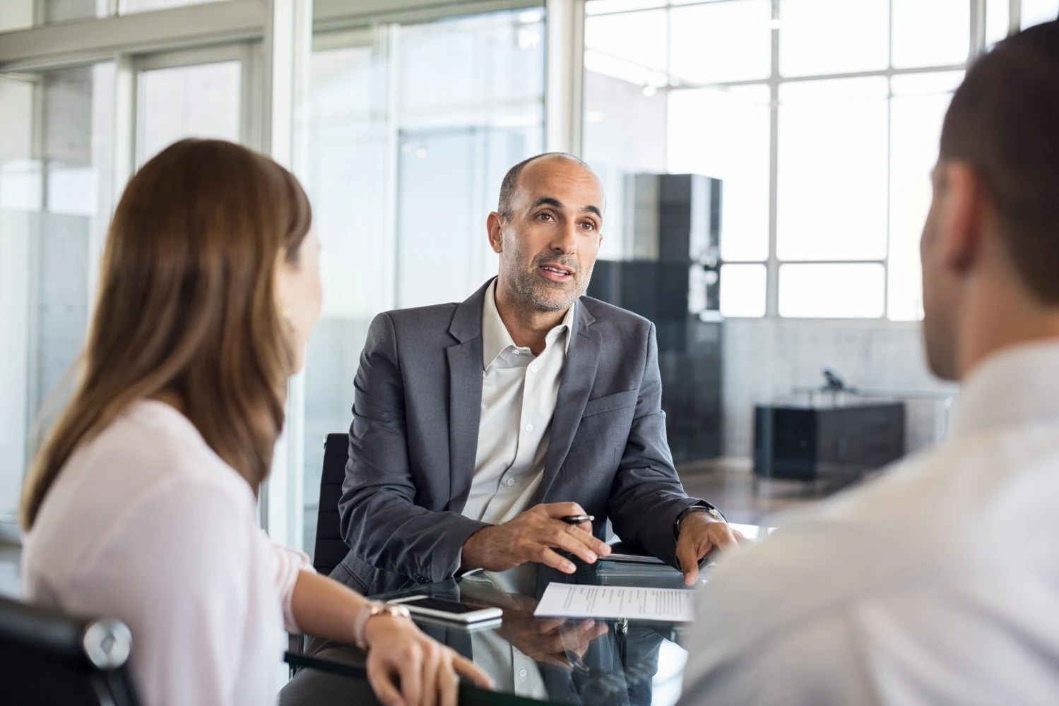 Nicotine consultant wearing suit discussing project with clients in modern office